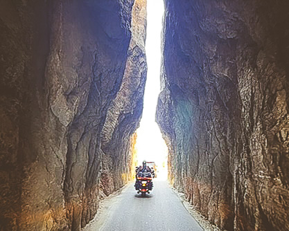 Motorcycle rider going through natural tunnel