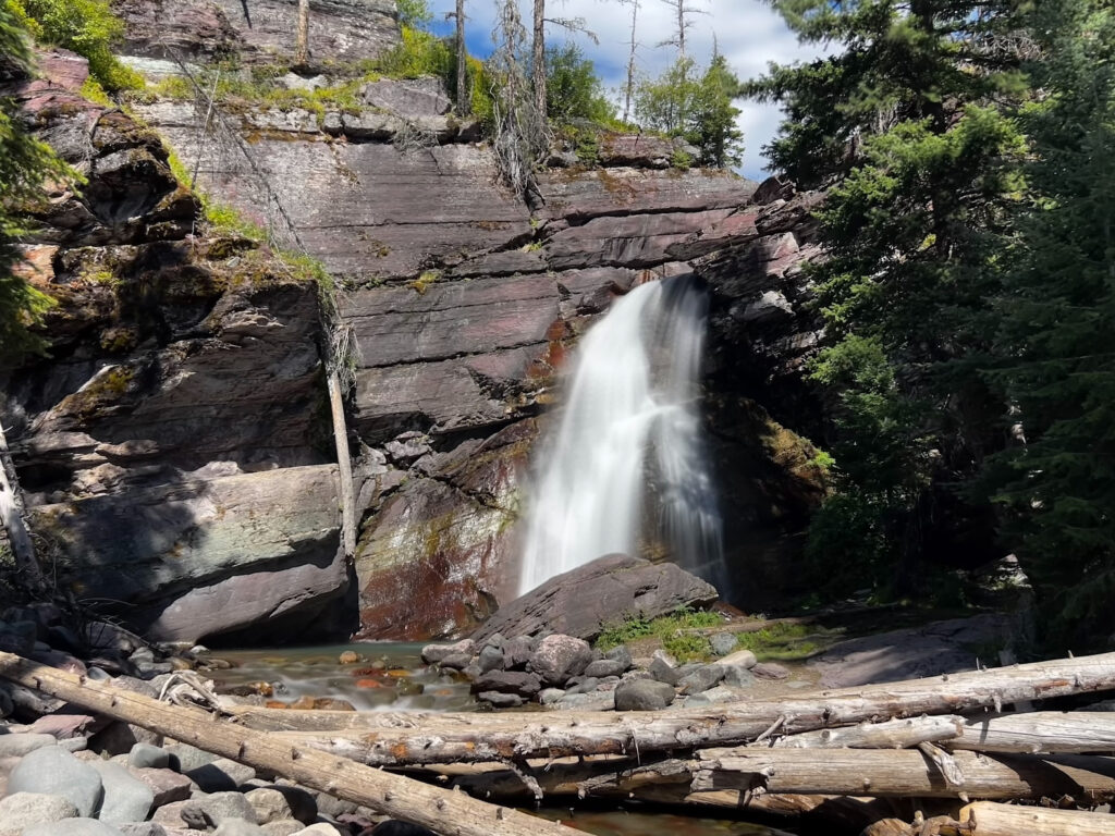 Water tumbles over jagged rocks, creating a misty spray that glistens in the sunlight.