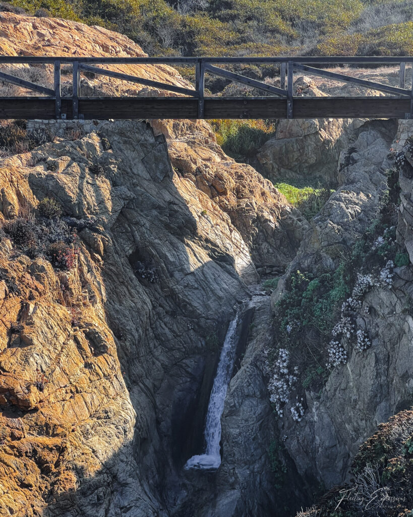 Waterfall flowing onto a beach from the cliffs.