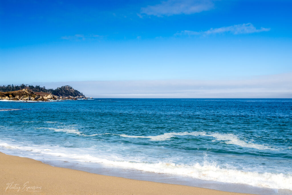 Beach with waves rolling in and a peninsula in the distance.