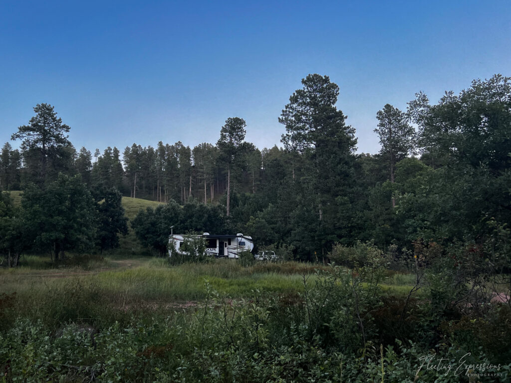 RV trailer in forest clearing at dusk